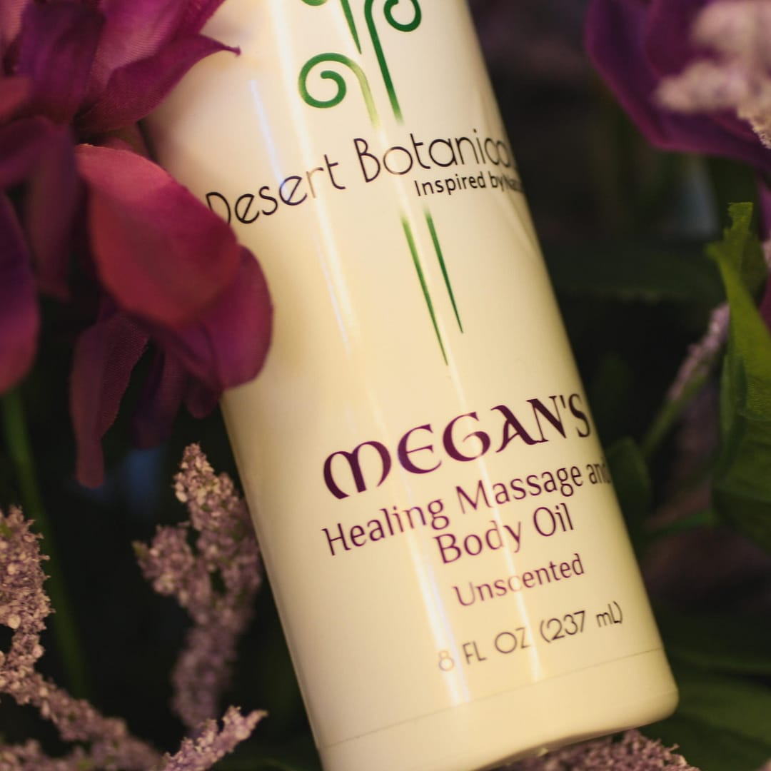 Bottle of Megan's Healing Massage and Body Oil with violet flower background