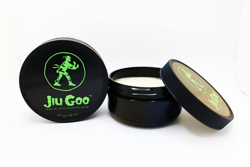 Jiu Goo™ product photo with jar on side to show top label and open jar with cap laying on top to show recovery balm