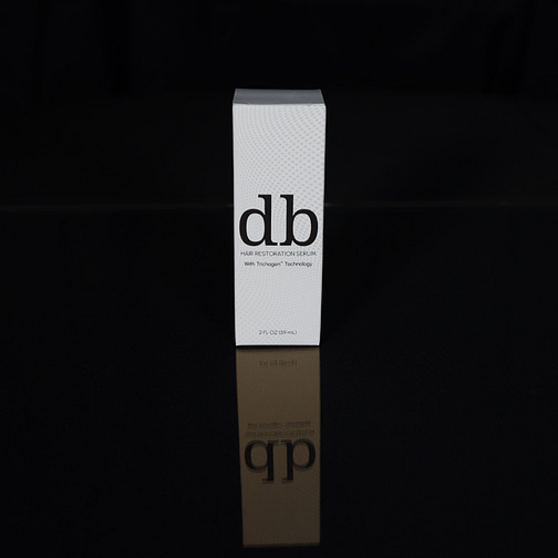 Box of two fluid ounce db Hair Restoration Serum with black background.